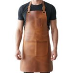 Caldo Maestro — Men's Warm Caramel Tan Genuine Full-Grain Cowhide Leather Heavy-Duty Adjustable Cross-Back Natural Strap Polished Silver-Tone Buckle Chest Pocket Large Front Multi-Pocket Chef Barber Blacksmith Craftsman Professional Workshop Utility Apron