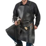 Nero Vulcano — Men's Jet Pitch Black Genuine Thick Heavy-Duty Rubber-Toughened Full-Grain Cowhide Leather Welding Forge Apron Adjustable Snap-Button Shoulder Strap Contrast Tan Stitch Wide Flared Lower Skirt Panel Side Torch Holder Tool Loop Brush Pocket Welder Blacksmith Farrier Foundry Forge Craftsman Industrial Heavy Workshop Utility Apron