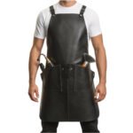 Nero Maestro — Men's Jet Black Genuine Smooth Glossy Full-Grain Cowhide Leather Heavy-Duty Adjustable Thin Cross-Back Shoulder Strap Black Hardware Clip Fastening Clean Minimal Bib Front Dual Deep Side Tool Pocket Scissor Holder Comb Slot Barber Hairdresser Stylist Chef Tattoo Artist Craftsman Sleek Professional Salon Workshop Utility Apron